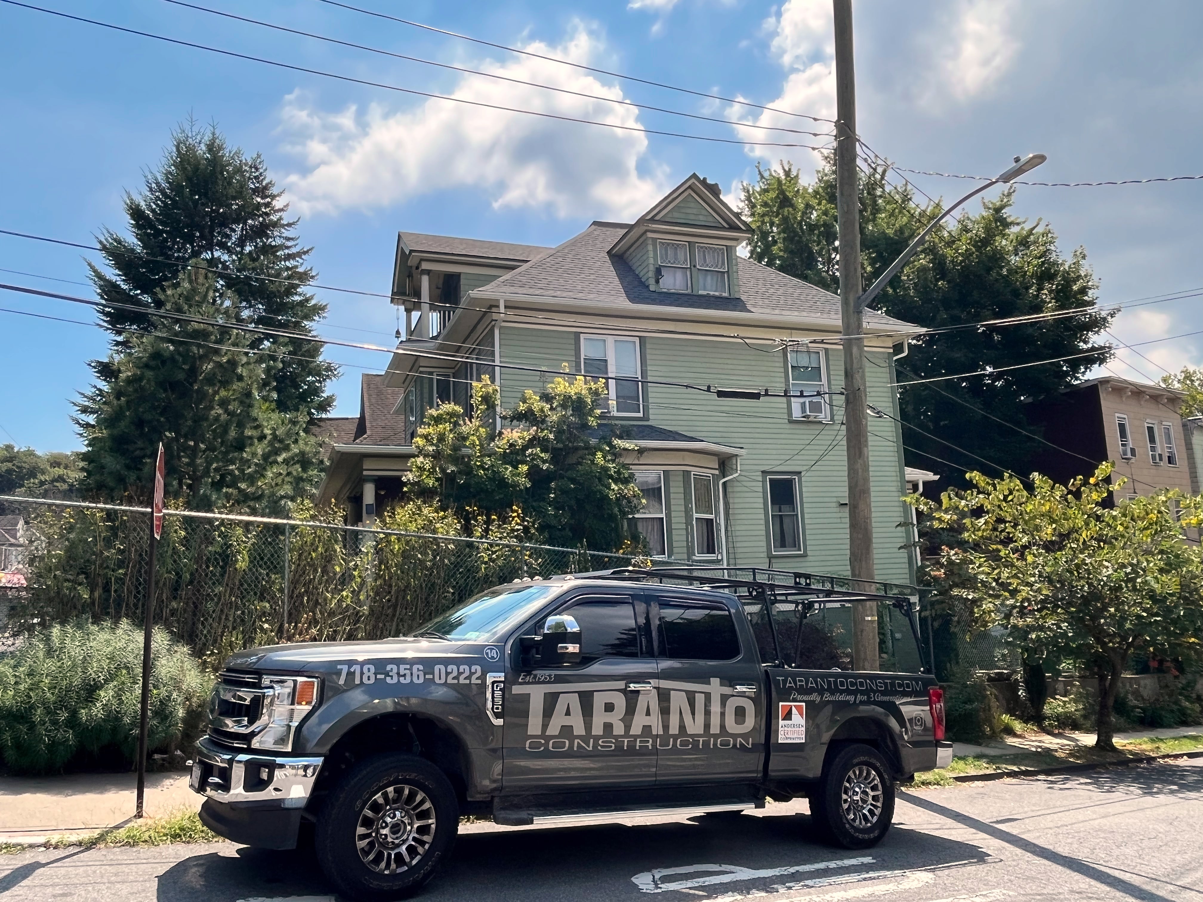 Gray Taranto Construction pickup parked in front of a green house